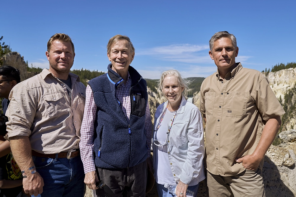 Four tour participants pose together with the Yellowstone River canyon in the background during the Senate Stewardship Caucus visit.