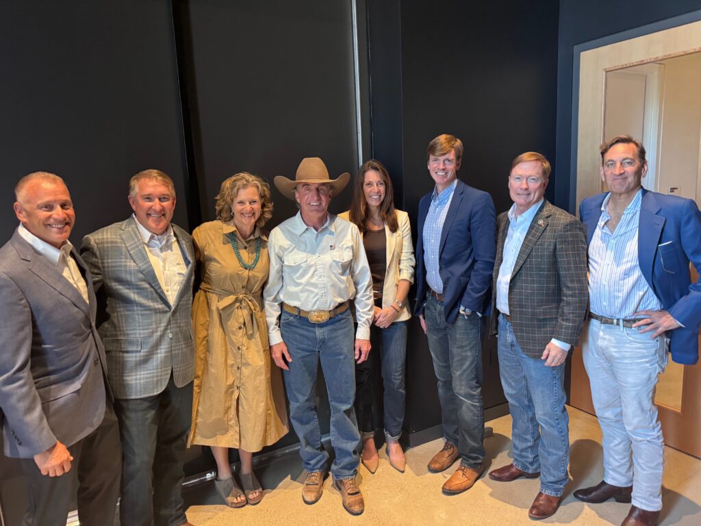 Panelists pose with Interior Secretary Doug Burgum, wearing a cowboy hat, backstage at the Theodore Roosevelt Presidential Library grand opening.