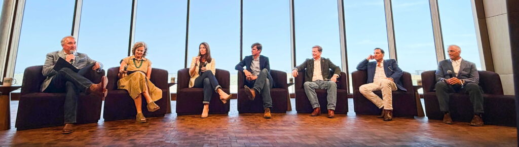 Seven conservation panelists seated in armchairs on stage in front of floor-to-ceiling windows at the Theodore Roosevelt Presidential Library, with PERC CEO Brian Yablonski moderating at left.