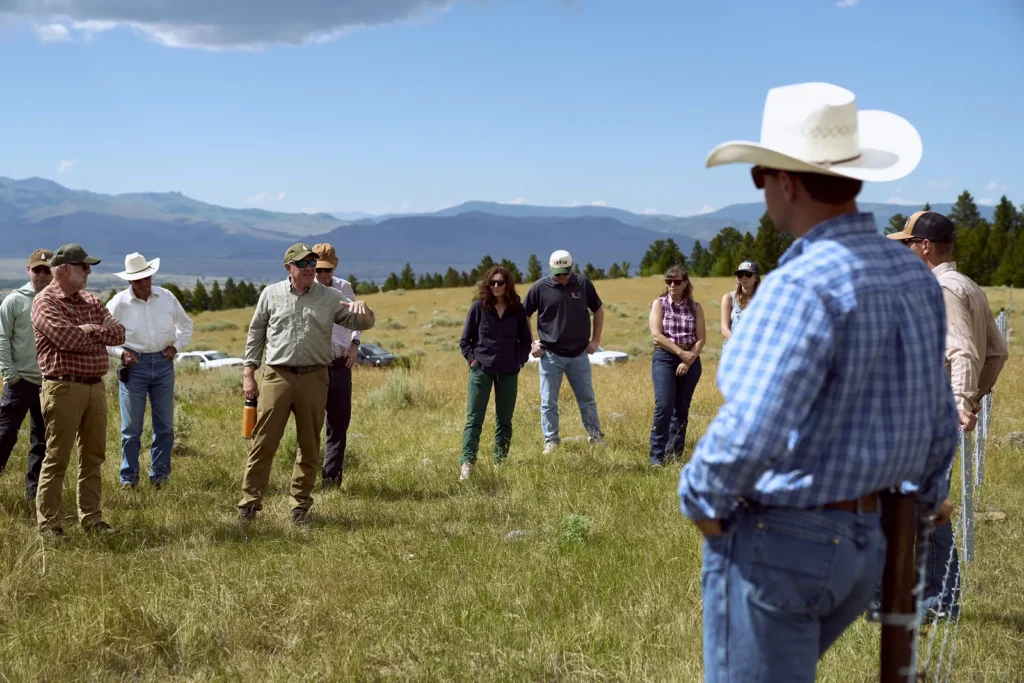 A rancher in a cowboy hat leads senators, agency officials, and conservation partners on a walking tour of grazing land at the Petrich Ranch in Paradise Valley.